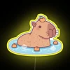 Adorable capybara relaxes in vibrant hot spring with orange hat.