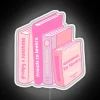 Neon LED sign featuring light pink romance tropes amidst book piles.