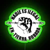 Neon protest sign against immigration policies on stolen indigenous land.
