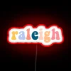 Raleigh cityscape illuminated with vibrant neon light and bold letters.