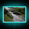 Vibrant Neon Sign Featuring Mossy Rocks and Gentle Stream Scene