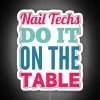 nail technicians performing services on a table under an rgb neon sign