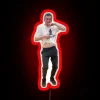 A nerdy boy dancing energetically under an RGB neon sign with vibrant red lighting.