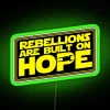 RGB neon sign displaying 'Of Rebellions and Hope II' in vibrant green colors.