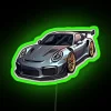 A sleek silver Porsche car with a cool anime-style neon RGB sign in vibrant green.