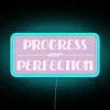 RGB Neon Sign Reading Progress Over Perfection with Vibrant Blue Glow.