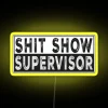 neon sign displaying shit show supervisor text with vibrant rgb lighting and yellow background