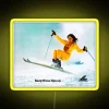 Neon sign with colorful ski girl illustration in vibrant yellow hue.