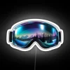 Winter sports gear with colorful ski goggles against a backdrop of northern lights reflections in the snow.