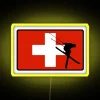 Neon ski patrol sign with yellow and RGB lighting on a mountain resort background.