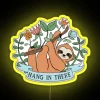 A sloth hanging from a bright neon "Hang in There" sign, surrounded by vibrant yellow accents.