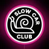 Neon pink road sign on a black background with a slow car club logo.
