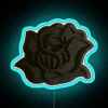 Close-up of a small black rose-shaped LED neon sign with blue accents illuminated at night.
