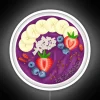 Acai smoothie bowl with mixed berries and granola in a vibrant purple neon-colored bowl, garnished with edible flowers.