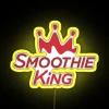 Neon sign reading Smoothie King Cafe in bold yellow letters against a dark background.