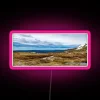 Snow-capped mountains under a vibrant pink neon glow at dusk.