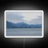 Neon-lit mountains under a blanket of snow at dusk.