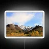 Mountainous landscape of Denali's snowy peaks illuminated by neon lights at sunset.