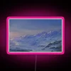 Neon pink sign with digital numbers displaying snowy mountain peaks in vibrant RGB colors at night.