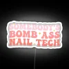Nail technician holding a bright neon sign with humorous nail art design.
