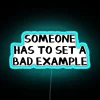 Vibrant neon sign with bold blue letters reading 'Someone Has to Set a Bad Example'.