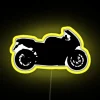 Sleek sport bike silhouette at dusk with vibrant neon lights in a yellow urban cityscape.