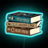 Stack of books with neon sign featuring the Prison Healer trilogy