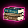 Stack of books with neon RGB lighting in pastel pink hue, inspired by The Prison Healer trilogy.