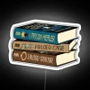 Stack of books with a futuristic, neon sign reading 'The Prison Healer Trilogy'