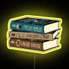 Stack of fantasy novels with neon signs, inspired by The Prison Healer Trilogy.