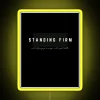 Neon sign with bold yellow letters reading 'Standing Firm'