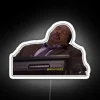 Stanley Hudson from The Office standing in front of a colorful neon sign.