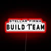 Dark neon sign reading 'Stellar Firma Build Team' in bold, futuristic letters.