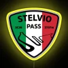 Motorcyclist navigating Stelvio Pass with a colorful LED neon sign on their bike at dusk.