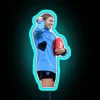 AFL player Steph Catley posing with a ball in front of a colorful neon sign
