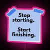 Neon pink sign with bold, cursive letters reading 'Stop, Start, Finish'