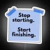 Neon light sign with bold, colorful letters displaying a motivational phrase about perseverance and completion.