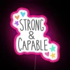 Neon sign with bold pink letters reading 'Strong and Capable' in a modern, vibrant font.