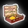 Colorful suitcase filled with vibrant summer accessories and a neon sign.