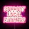 Neon sign supporting local farmers with pink and green colors against a dark background.