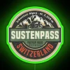 Neon sign reflecting off Susten Pass mountain road at sunset.