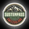 Neon sign at Susten Pass, Switzerland, lit up in white against a dark mountainous backdrop at night.
