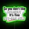 Neon sign reading 'Sut-Ure Self-Surgery Pun' in green letters.