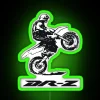 A rider performing a wheelie on a Suzuki DR-Z bike in front of a colorful neon sign.