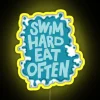 Neon sign reading "Swim Hard Eat Often" in bright yellow letters against a dark background.