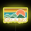 A neon sign with a bold, yellow font reading 'Take A Hike' in a modern style.