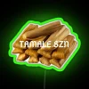 Neon sign featuring colorful tamale-themed graphics in a vibrant, green-toned design.