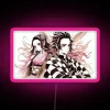 Tanjiro and Nezuko standing in front of a vibrant pink neon sign.