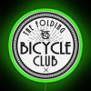 The logo of The Folding Bicycle Club featuring a neon sign with a green background.