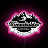 Neon sign in black and pink hues illuminating The Remarkables mountain range at dusk.